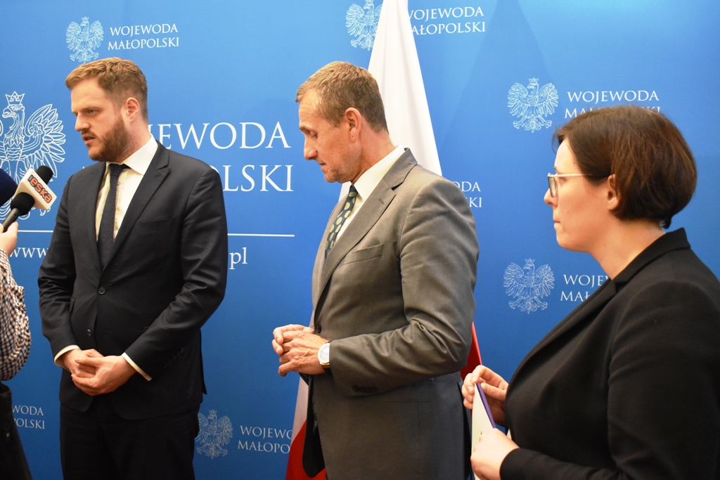 zdjęcie przedstawiające trzy osoby stojące na tle ścianki Urzędu Wojewódzkiego - wiceminister zdrowia, wicewojewoda, zastępca Dyrektora MOW NFZ ds.medycznych